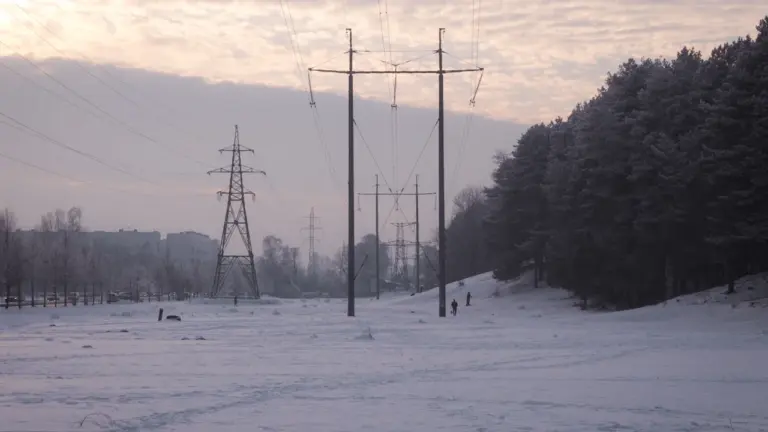 Augstsprieguma elektrolīnijas Latvijas ziemas ainavā, simbolizējot elektroenerģijas sadali un energoapgādes infrastruktūru.