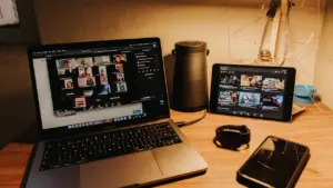 Portatīvais dators uz koka galda, kurā redzama tiešsaistes videokonference ar daudziem dalībniekiem.
