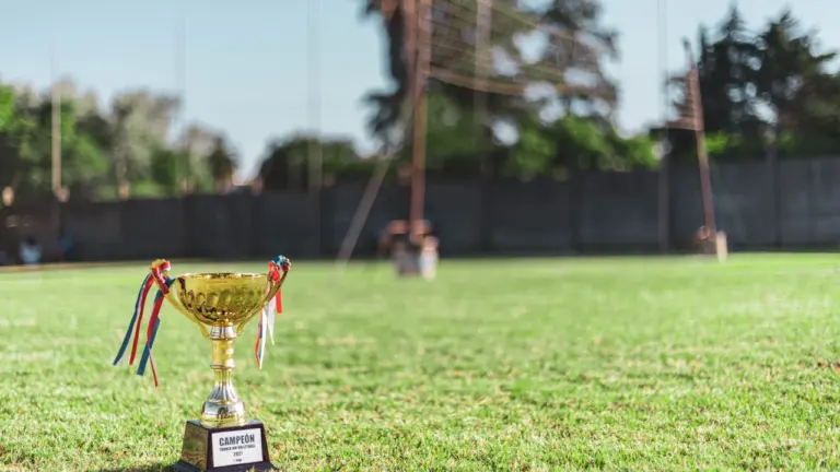 Mirdzošs čempionu kauss uz zaļa golfa laukuma pirms 2026. gada Ryder Cup turnīra.
